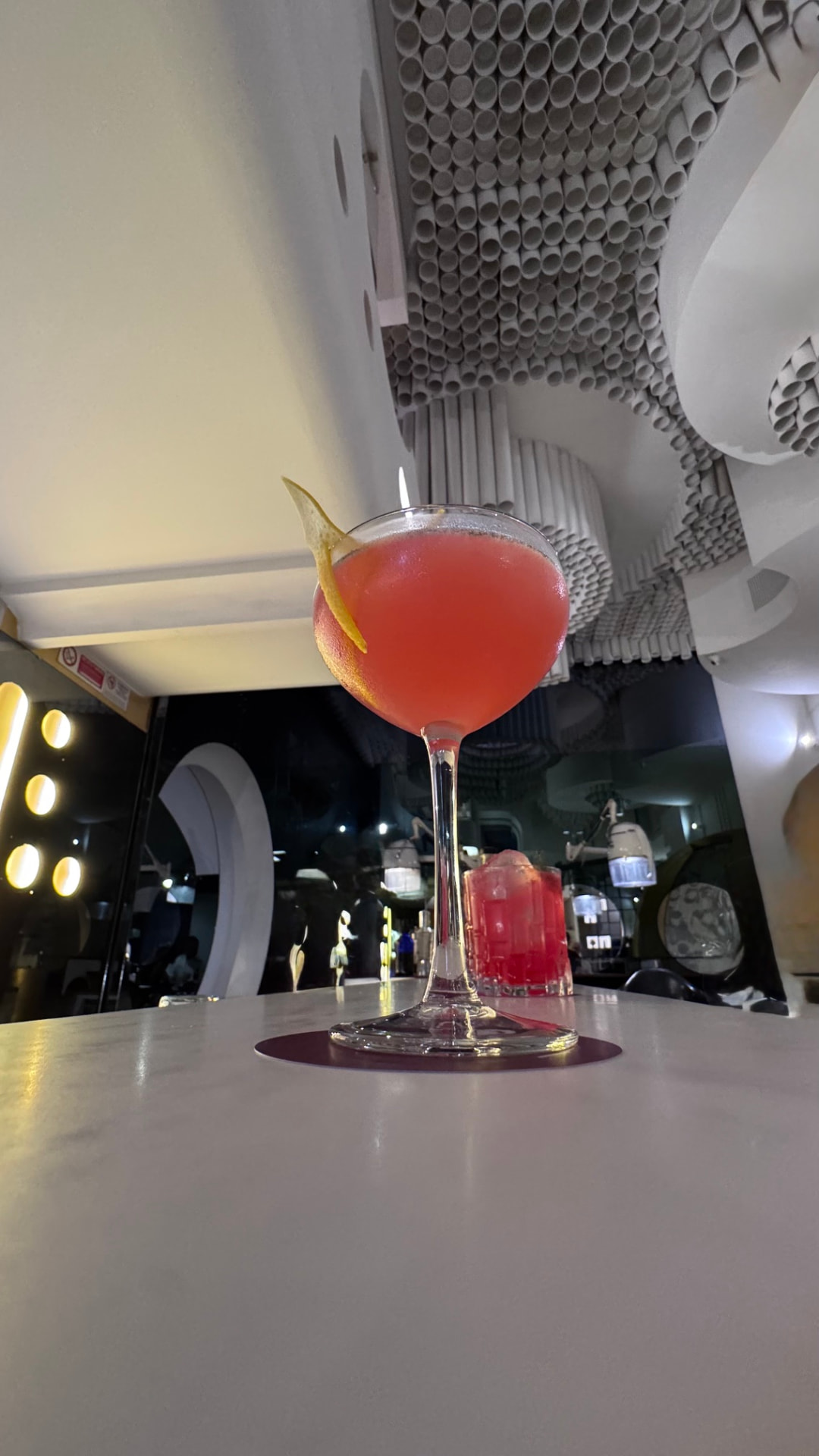 Cocktail rosso servito in coppa sotto il soffitto anni Settanta