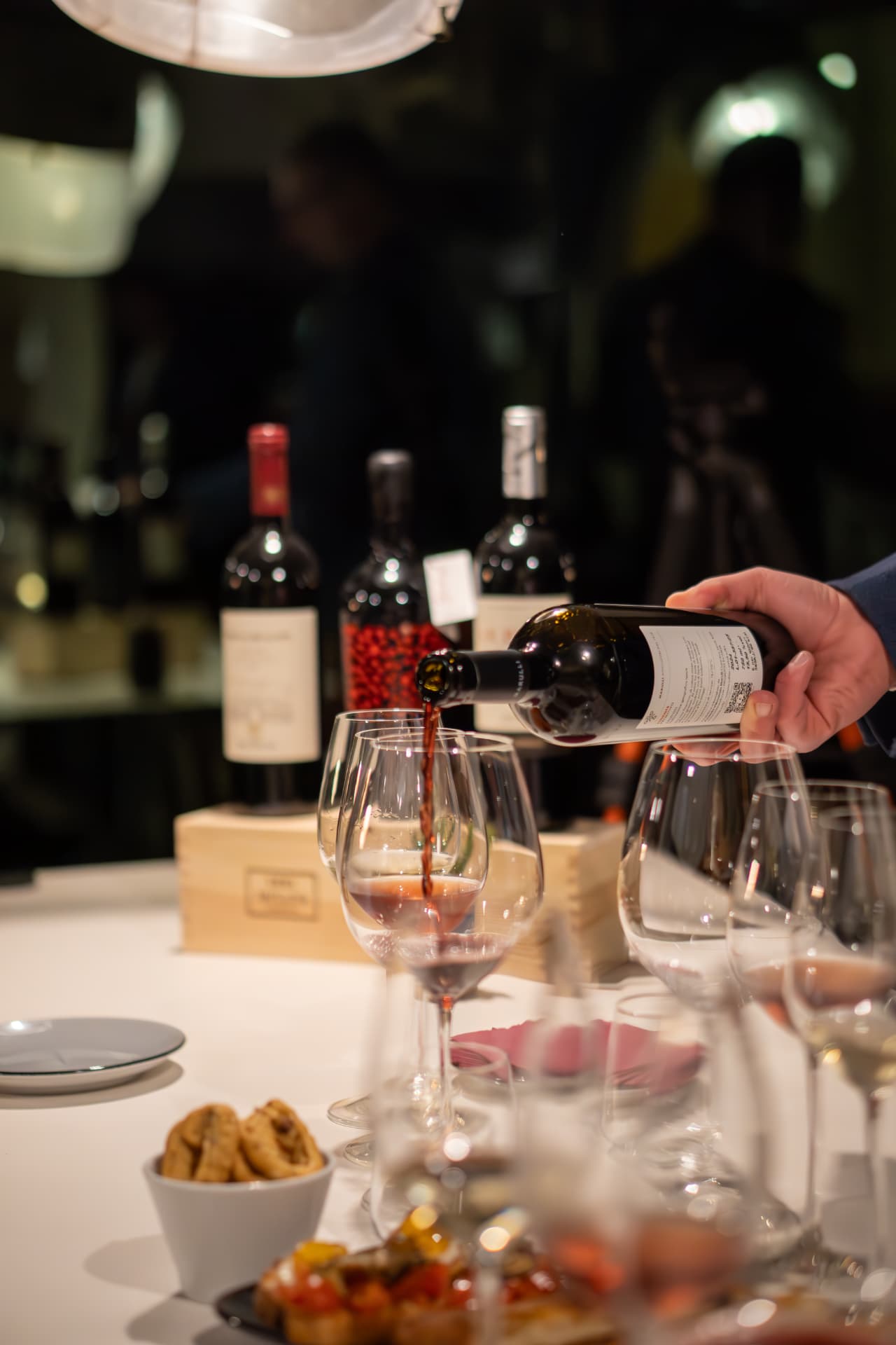 Vino rosso versato accanto alle bottiglie in degustazione
